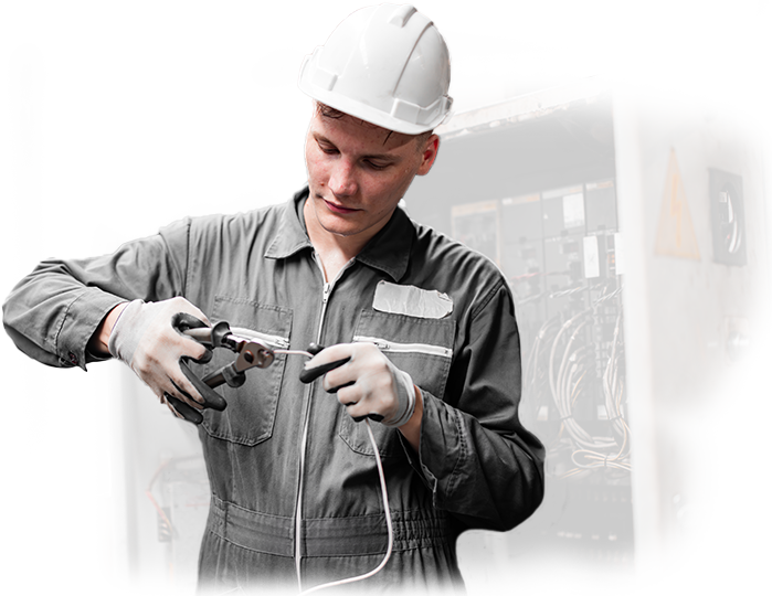 A man in a hard hat is cutting a wire with scissors.