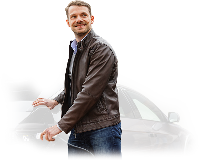 A man in a leather jacket is charging an electric car