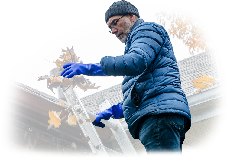 A man wearing blue gloves is cleaning a gutter on a roof.