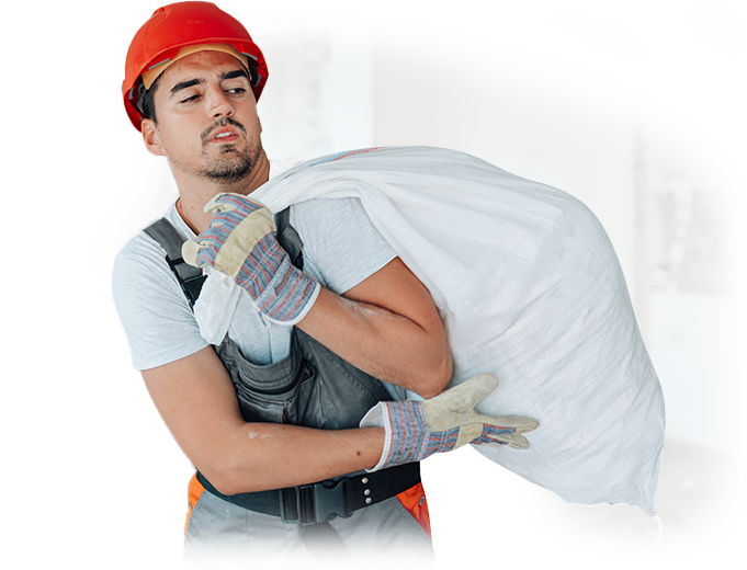 A man wearing a hard hat and gloves is carrying a bag.