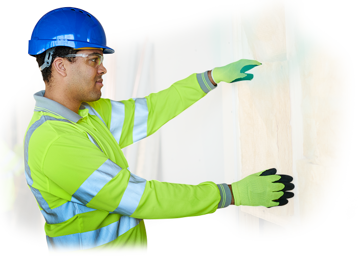 A man wearing a hard hat and gloves is pointing at a piece of insulation