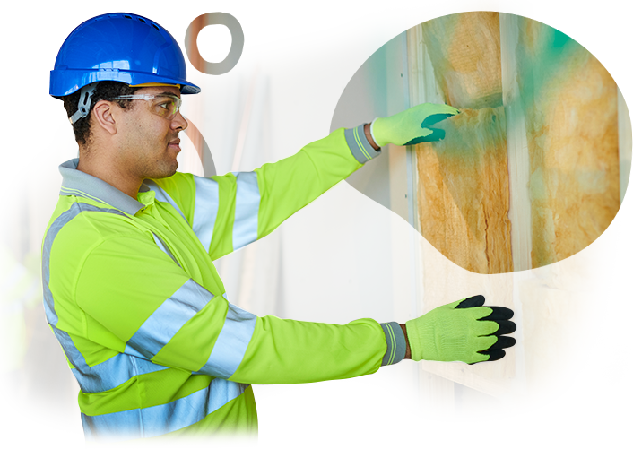 A man wearing a hard hat and gloves is pointing at a piece of insulation