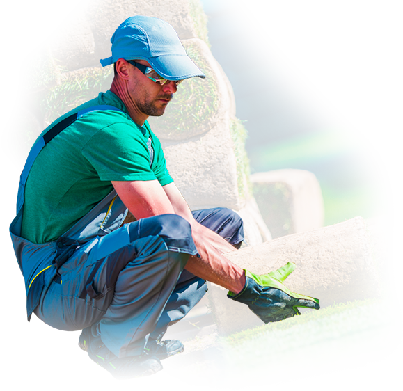 A man in a green shirt and blue hat is kneeling down