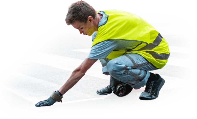 A man in a yellow vest is kneeling down on the ground.