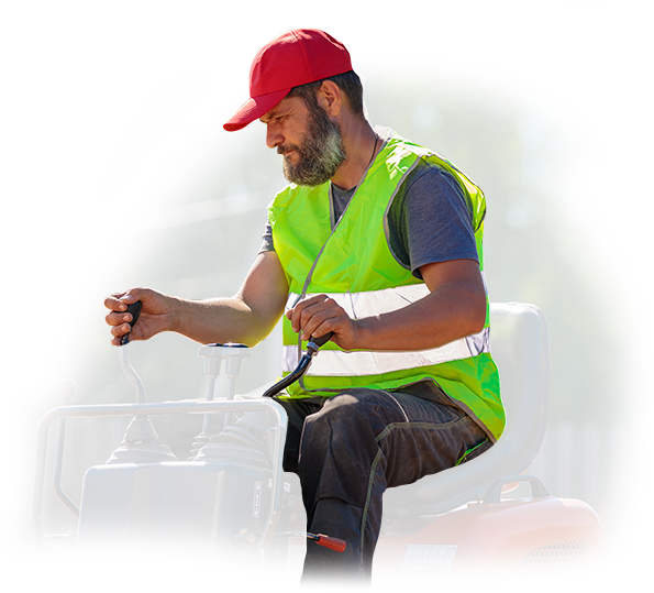 A man in a green vest and red hat is driving a tractor.