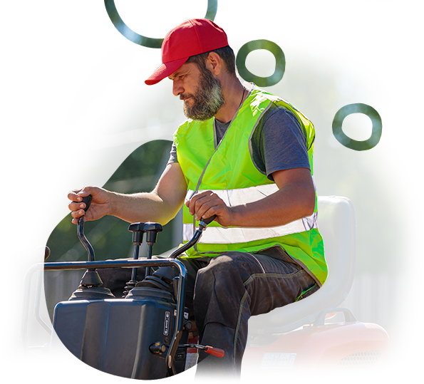 A man in a green vest and red hat is driving a tractor.