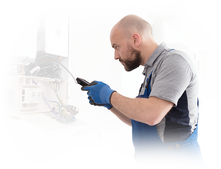 A man is working on a boiler with a hose.