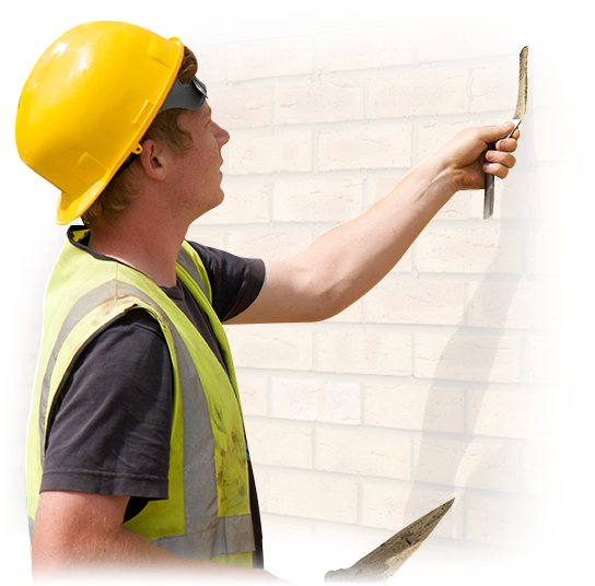 A man wearing a yellow hard hat and safety vest is working on a brick wall