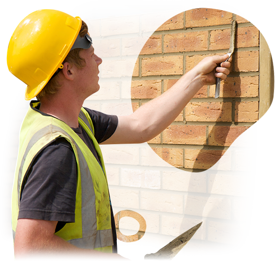 A man wearing a yellow hard hat and safety vest is working on a brick wall