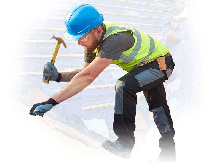 A man wearing a hard hat is working on a roof with a hammer.