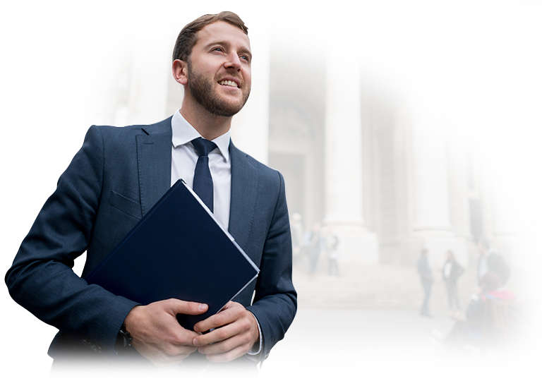 A man in a suit and tie is holding a book in front of a building.
