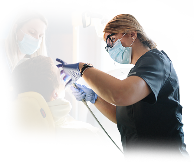 A female dentist is examining a young boy 's teeth