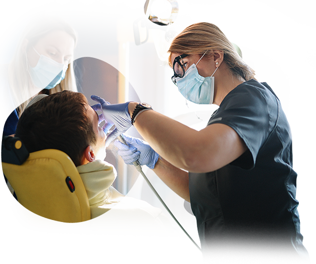 A female dentist is examining a young boy 's teeth