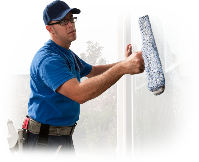 A man wearing blue gloves is cleaning a gutter on a roof.