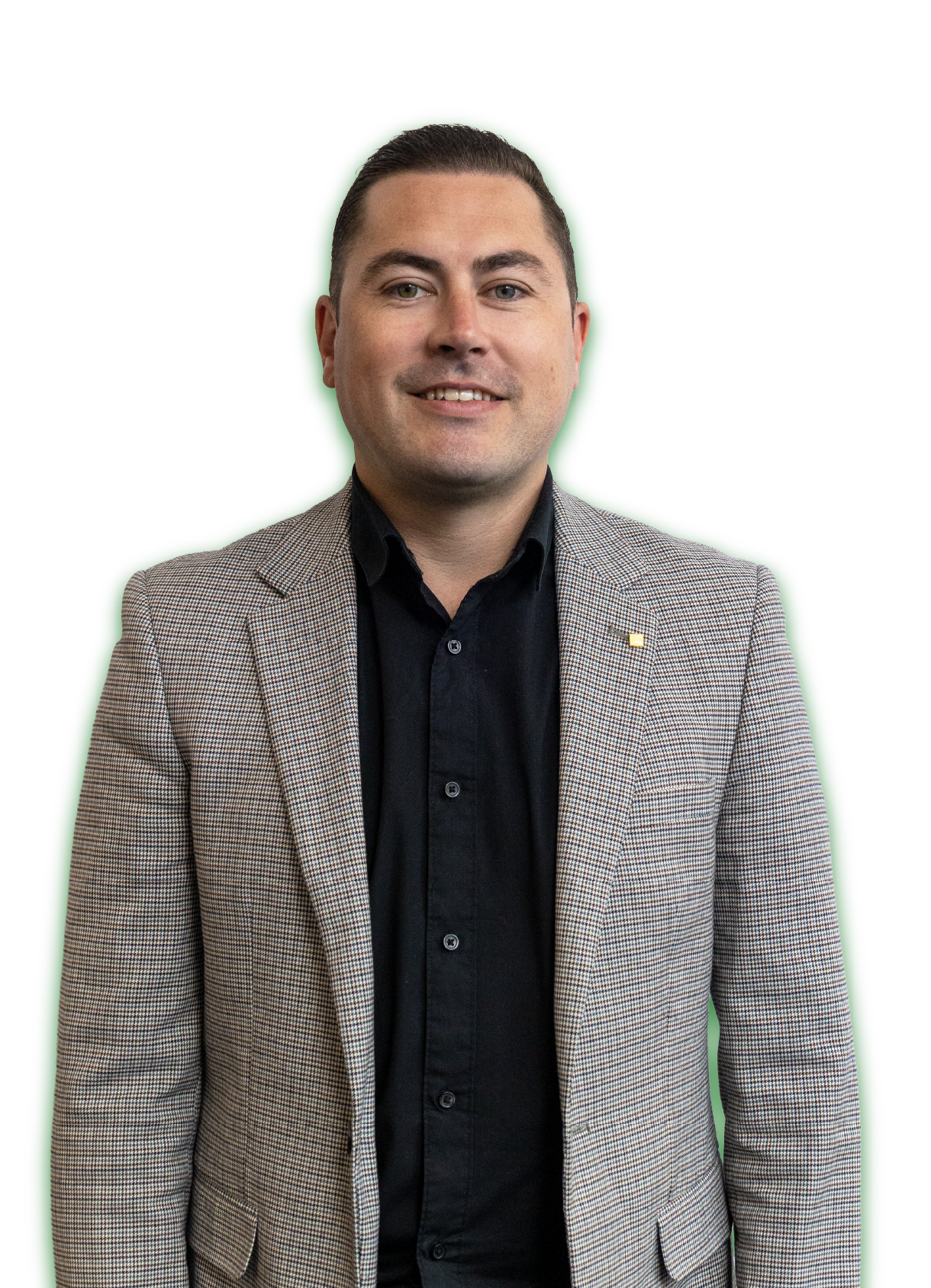 Man in blazer smiling at the camera; standing against a white background.