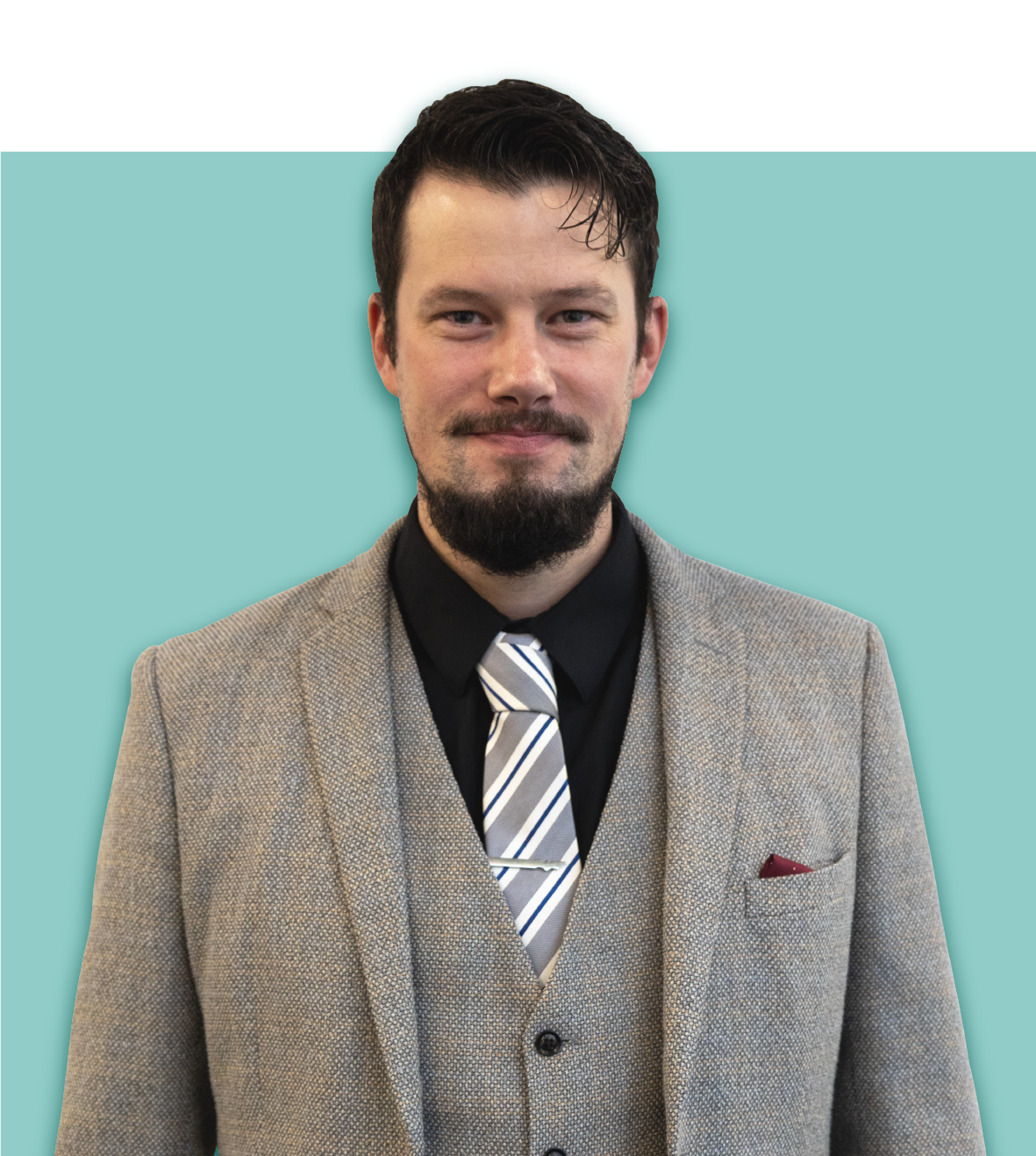 A man in a suit and tie is standing in front of a blue background.