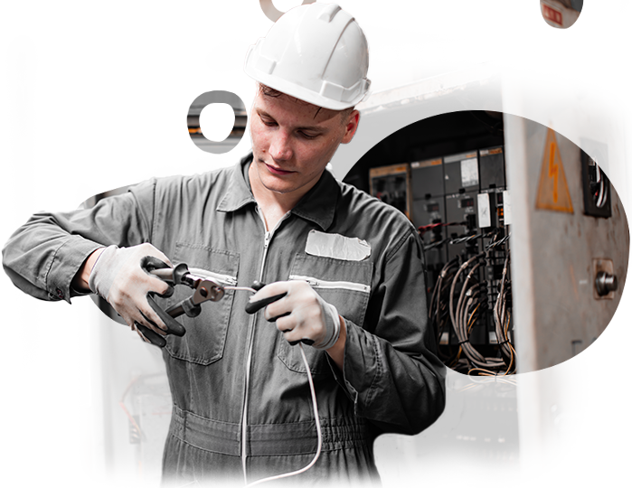A man in a hard hat is cutting a wire with scissors.