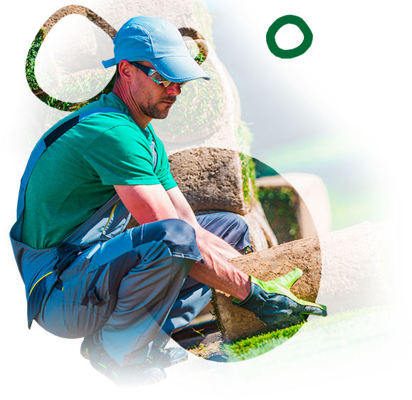 A man in a green shirt and blue hat is kneeling down