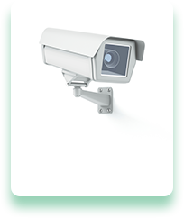 A security camera is mounted to a wall on a white background.