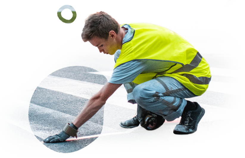 A man in a yellow vest is kneeling down on the ground.