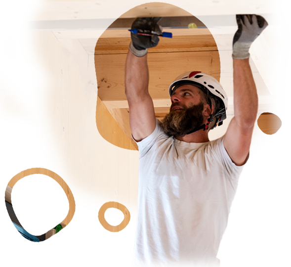 A man with a beard wearing a helmet and gloves is working on a ceiling