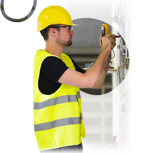 A man wearing a hard hat and safety vest is using a multimeter