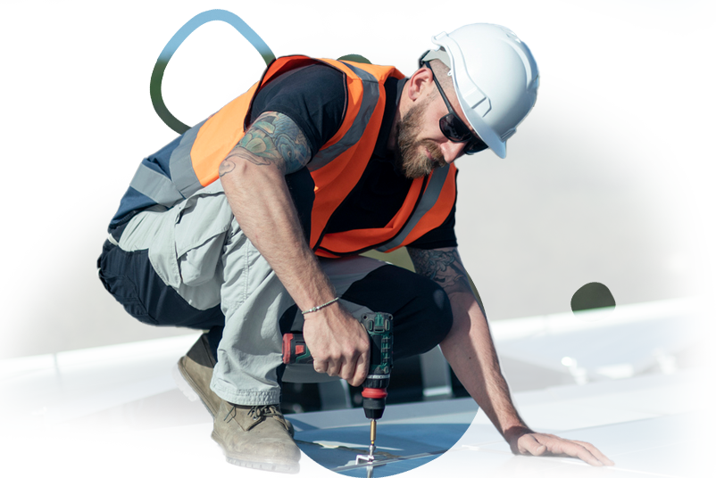 A man wearing a hard hat and safety vest is using a drill.