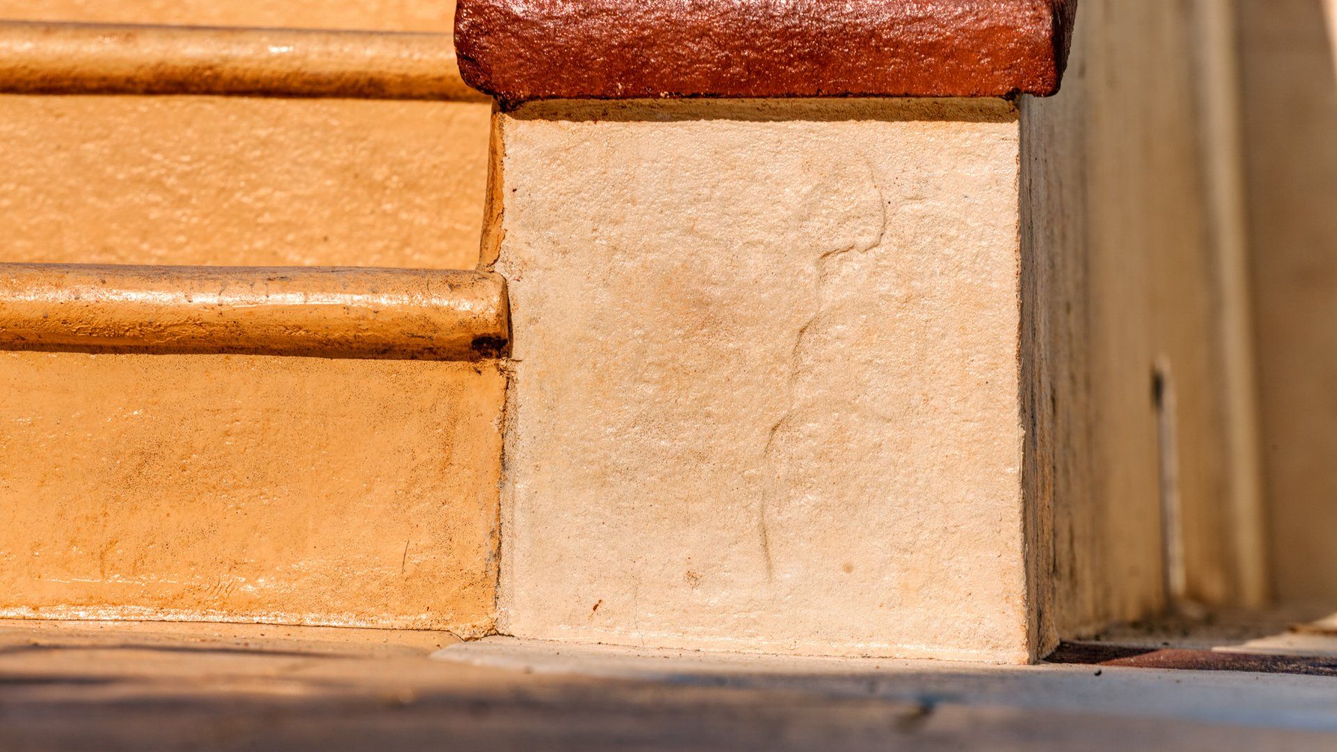 Closeup picture of terracotta coloured concrete stairs.  The steps have a brown coloured border.