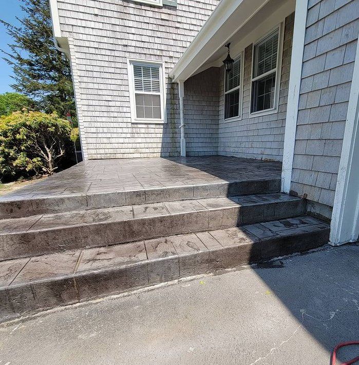 Picture of concrete steps leading from a concrete patio up to a deck.