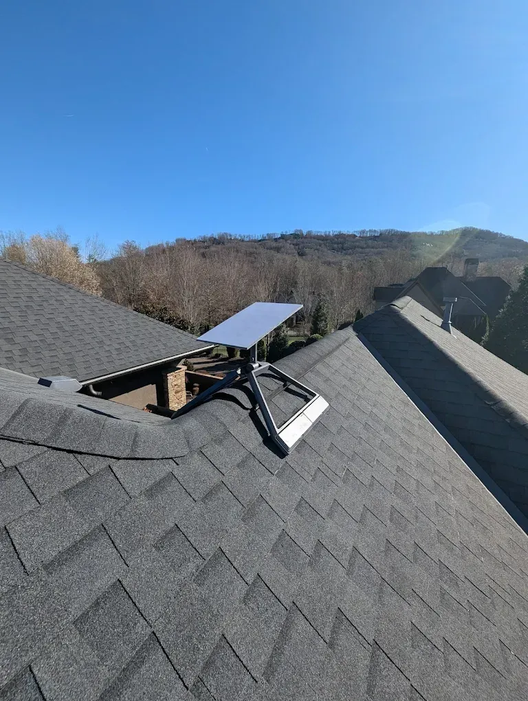 A solar panel is sitting on the roof of a house.