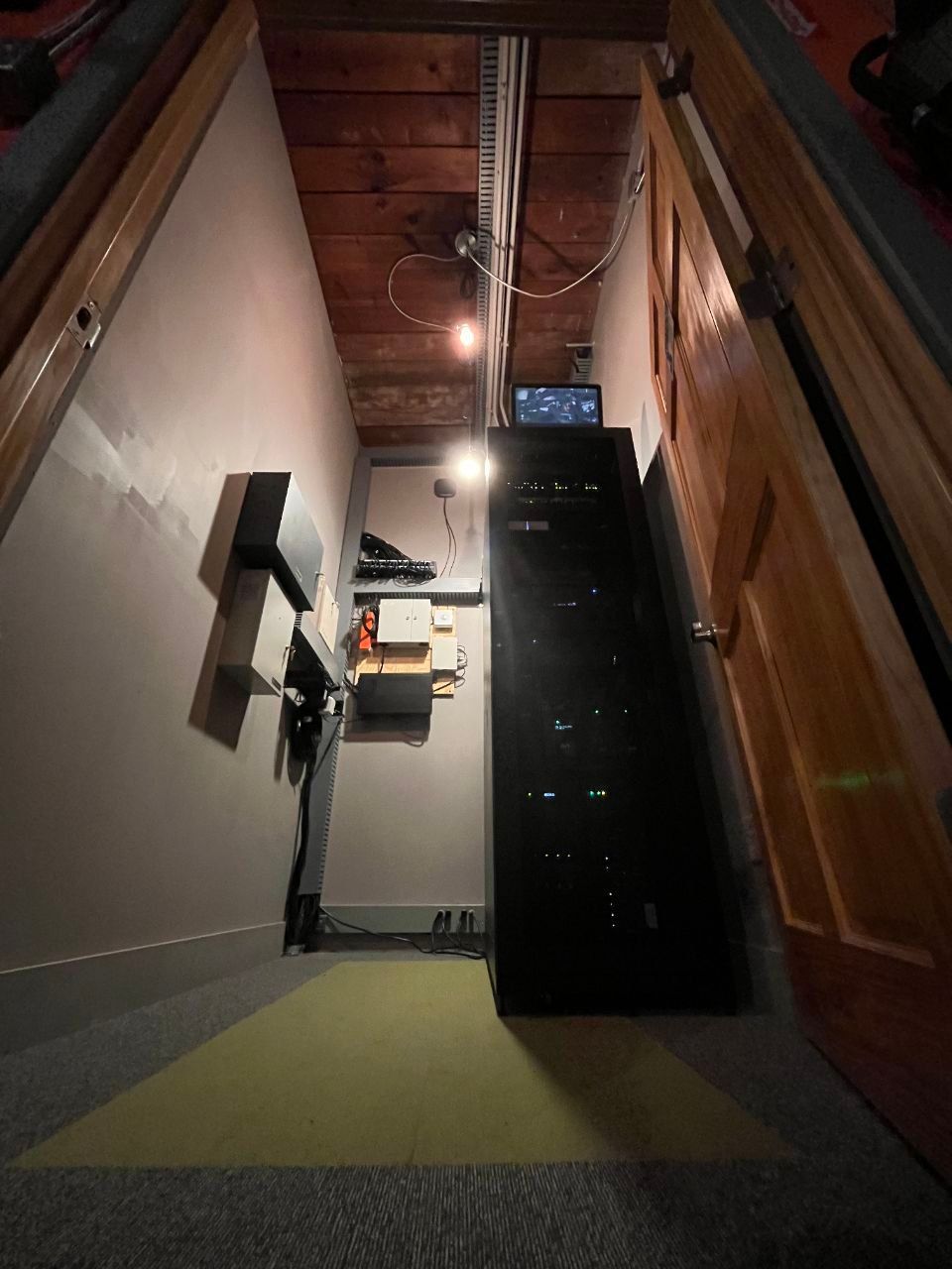 A narrow hallway with a wooden ceiling and a black cabinet
