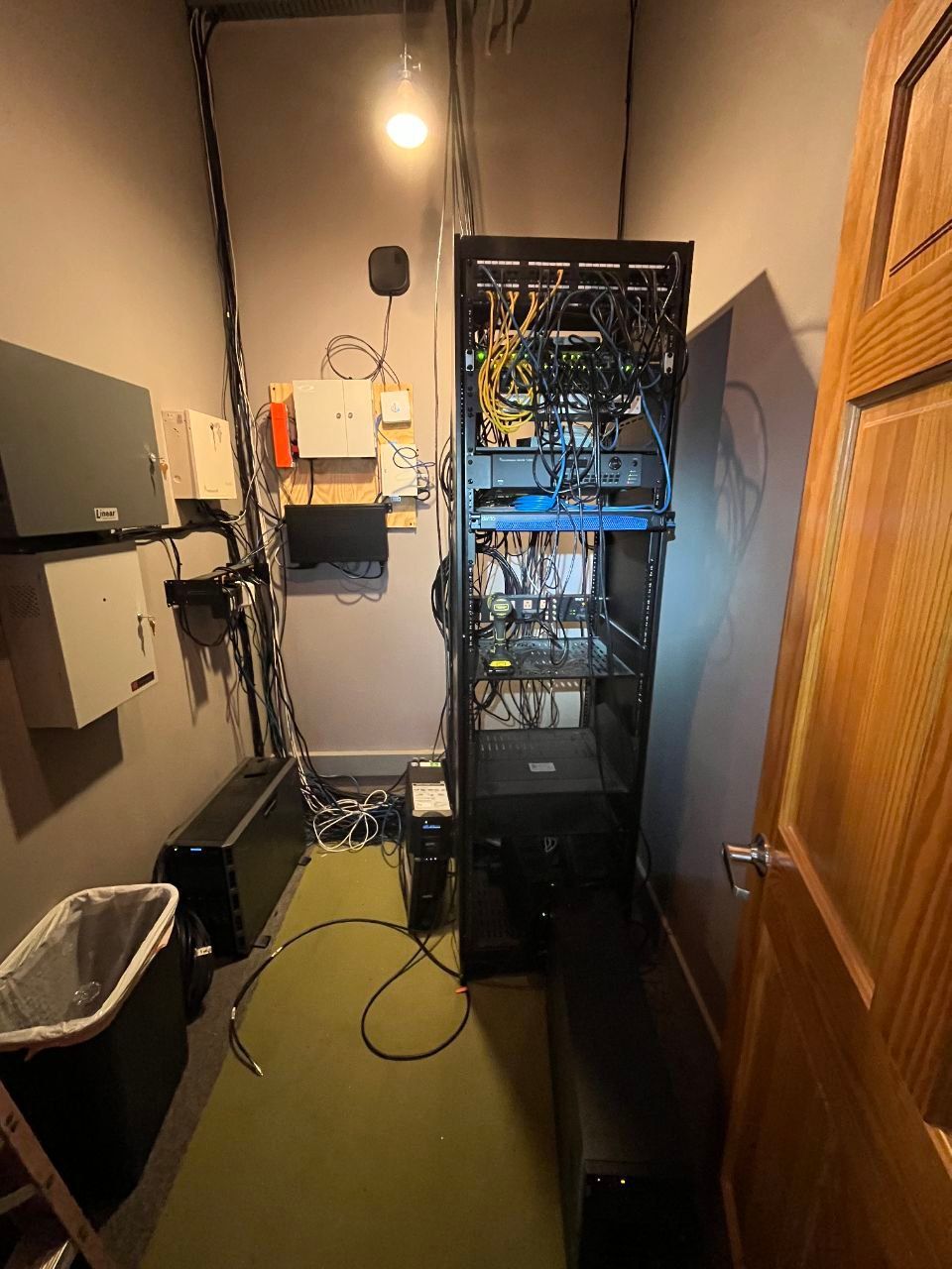 A room with a lot of wires coming out of it and a trash can.