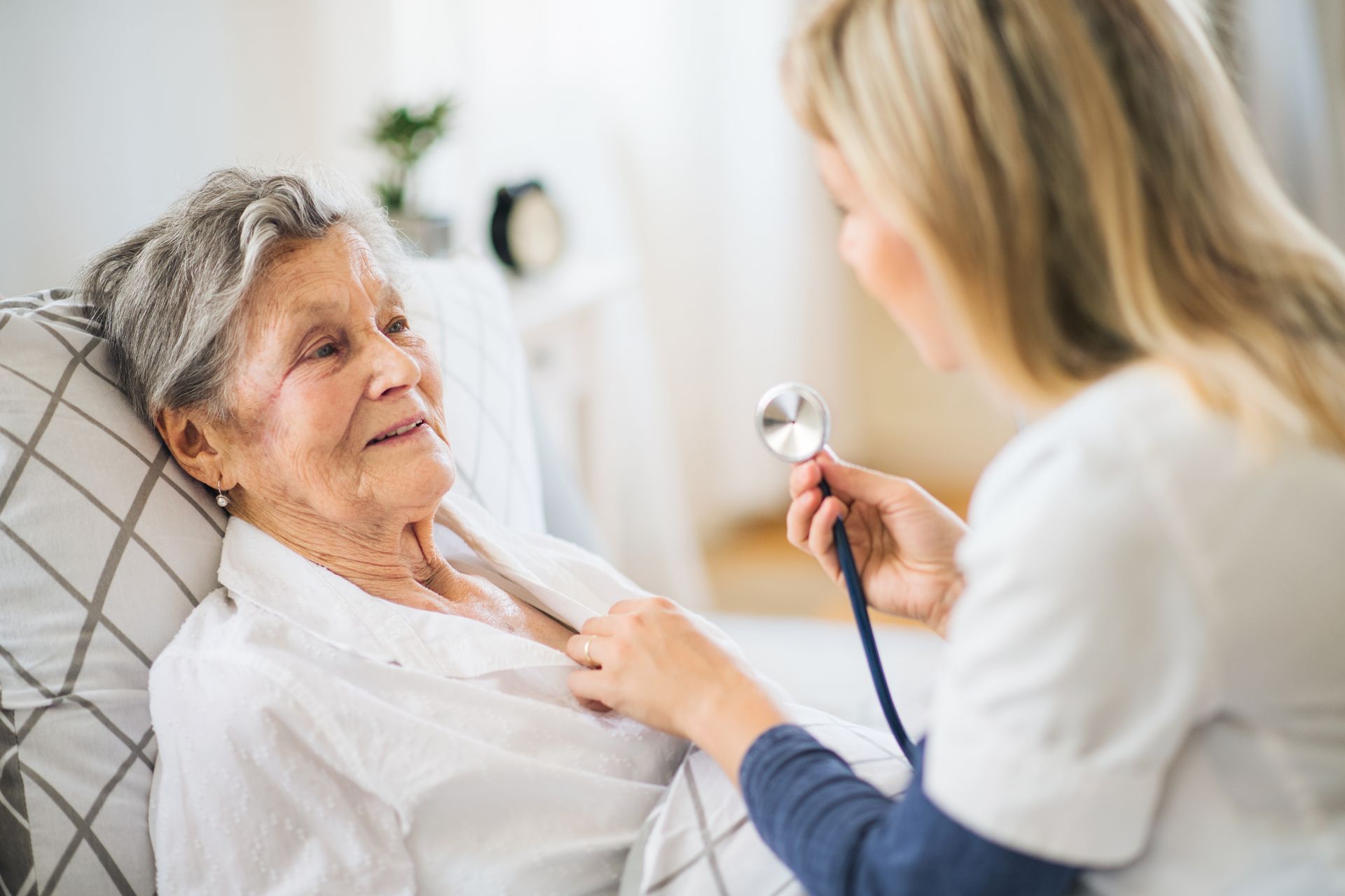 A nurse assesses an elderly woman's heart, highlighting the importance of home health care service.
