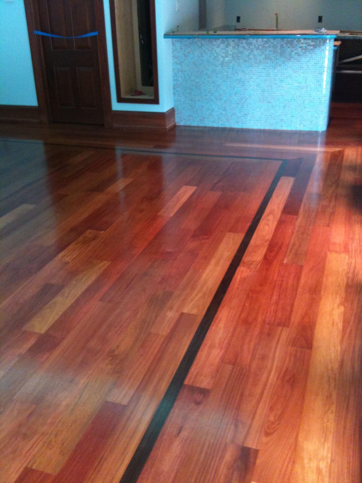 Shiny hardwood floor in an empty room with a blue wall and wooden door.