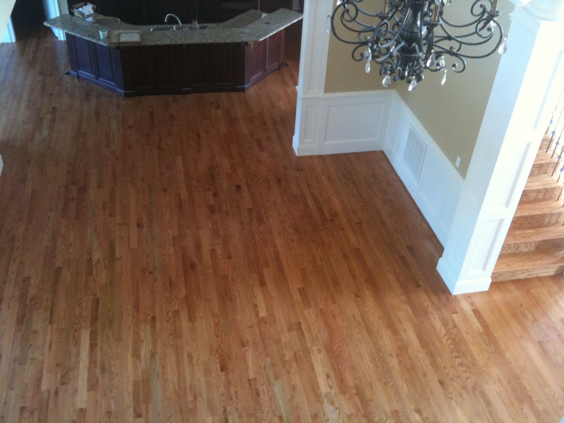 Empty room with hardwood floor, a fireplace, and a chandelier in the corner.