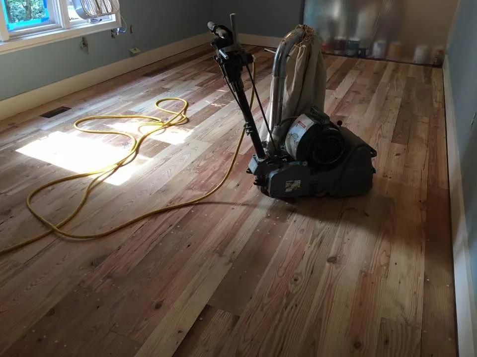 Vacuum cleaner on a hardwood floor in an empty room, with cords near a window.