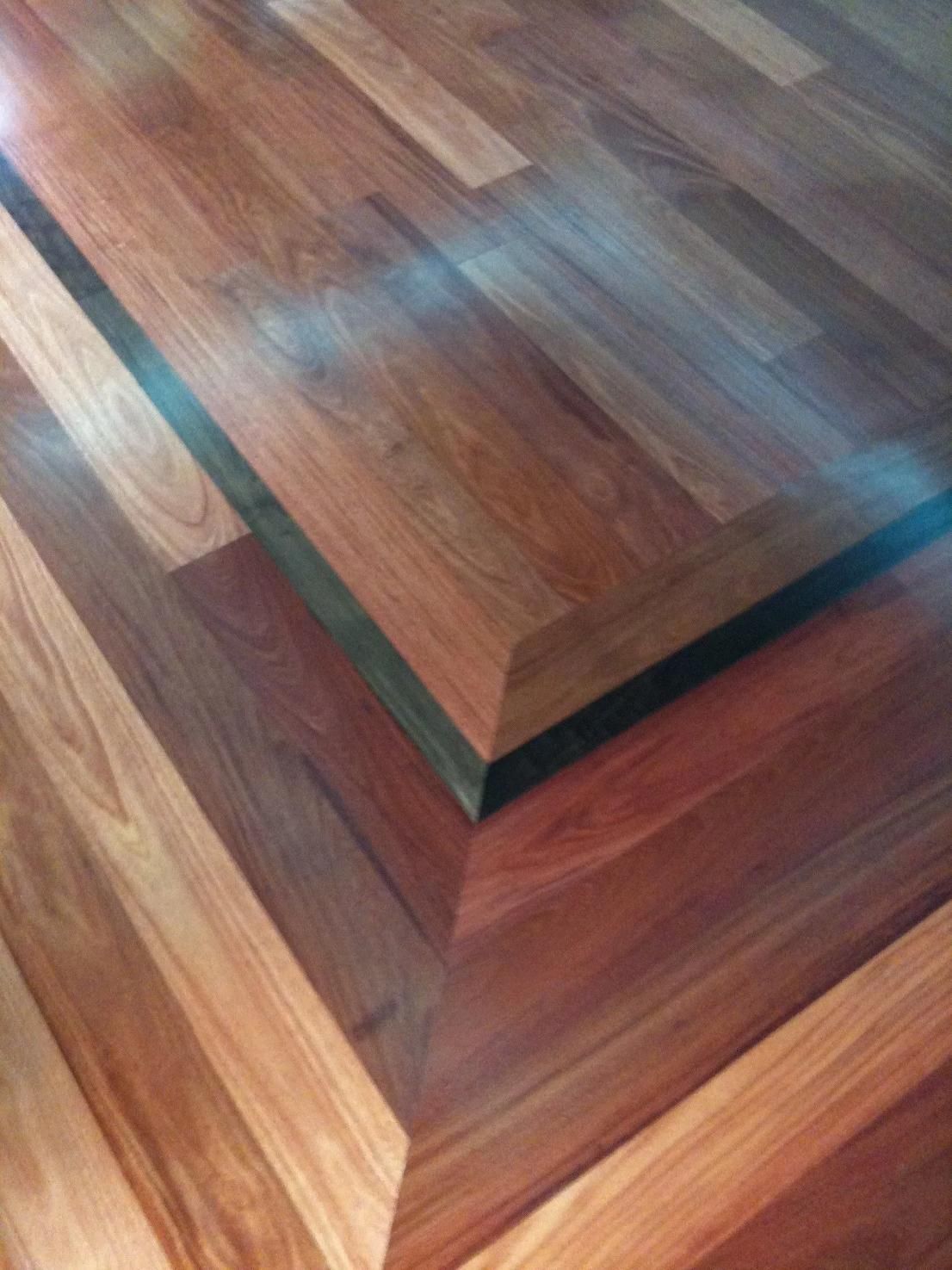 Close-up of polished wooden stairs with reddish and dark brown planks in geometric patterns
