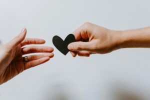 Two people are holding black hearts in their hands.