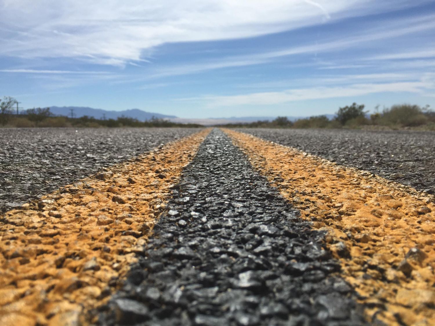 Road stretching into the distance under a blue sky, with yellow lines down the middle.