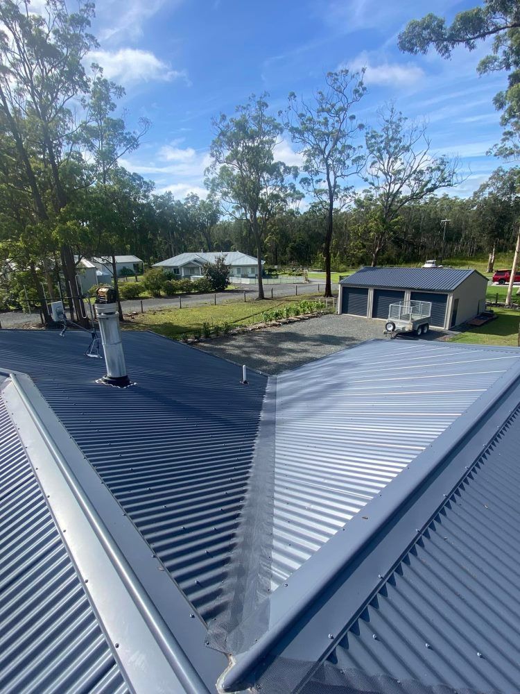 A Roof With A Chimney On It And A Garage In The Background — The Guttering Cleaning Man in Pacific Palms, NSW