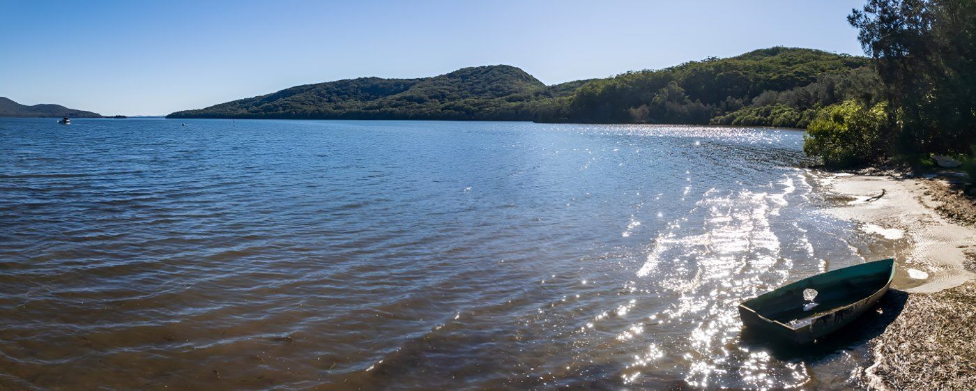 A boat is sitting on the shore of a lake.