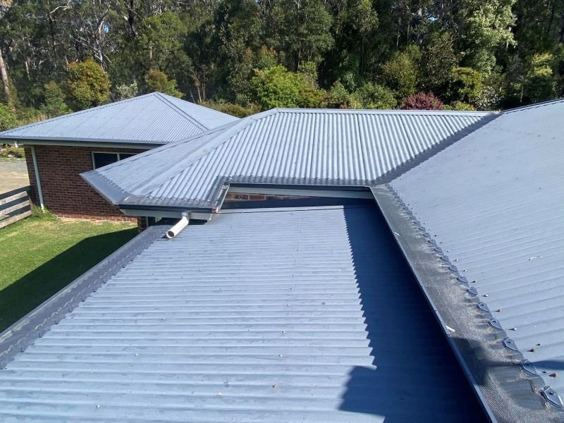 A House With A Blue Roof And A Black Gutter — The Guttering Cleaning Man in Forster, NSW