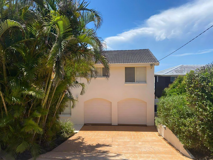 A White House With A Driveway And Palm Trees In Front Of It — The Guttering Cleaning Man in Forster, NSW