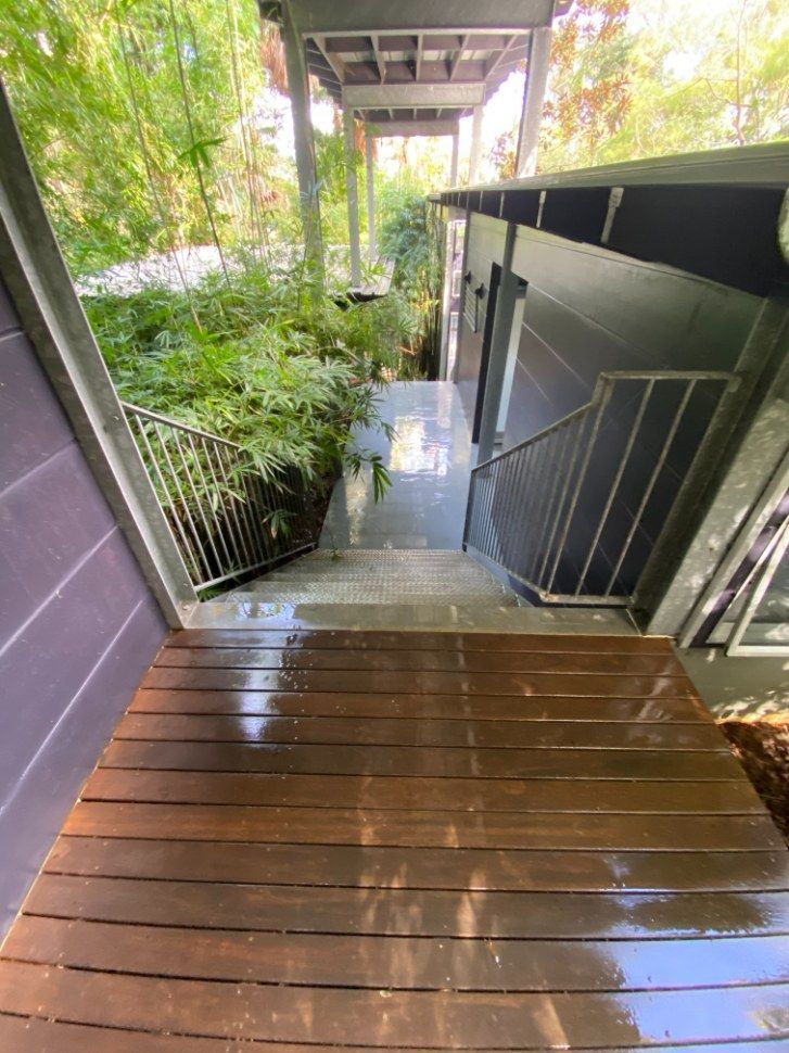 A Wooden Deck With Stairs Leading Up To A House — The Guttering Cleaning Man in Forster, NSW