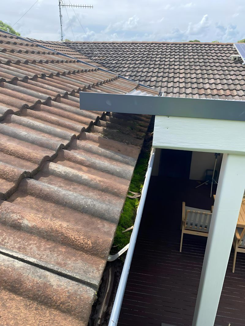 There Is A Gutter On The Side Of The Roof Of A House — The Guttering Cleaning Man in Taree, NSW