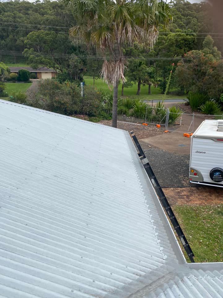 A Man Is Using A High Pressure Washer To Clean A Concrete Floor — The Guttering Cleaning Man in Pacific Palms, NSW