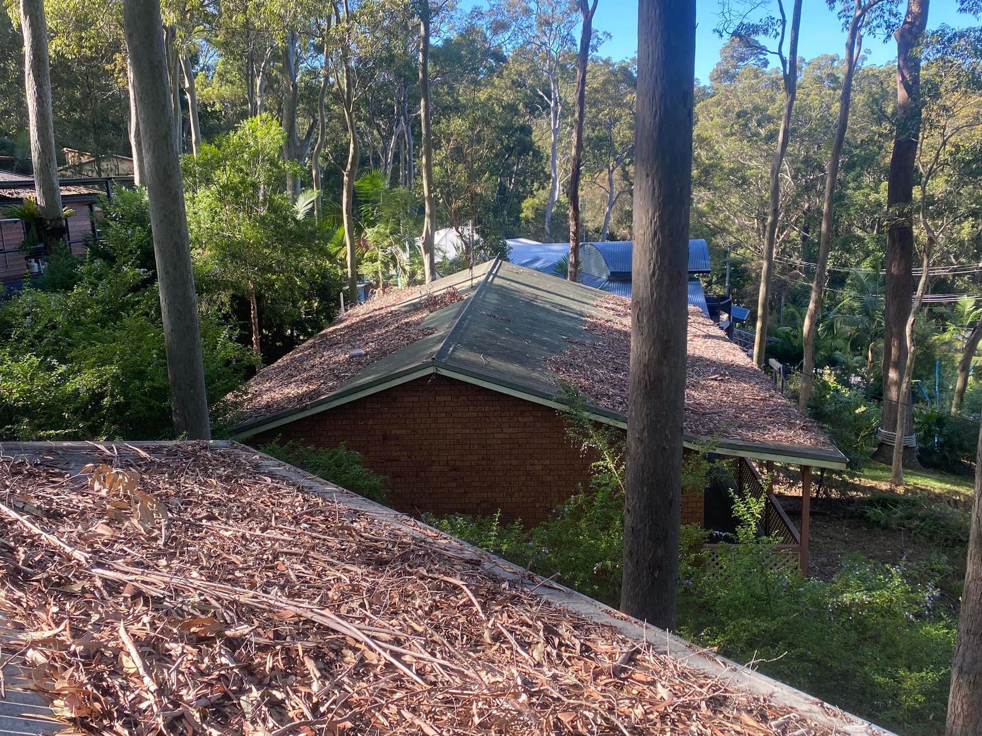 A Person Is Cleaning A Wooden Fence With A High Pressure Washer — The Guttering Cleaning Man in Nabiac, NSW