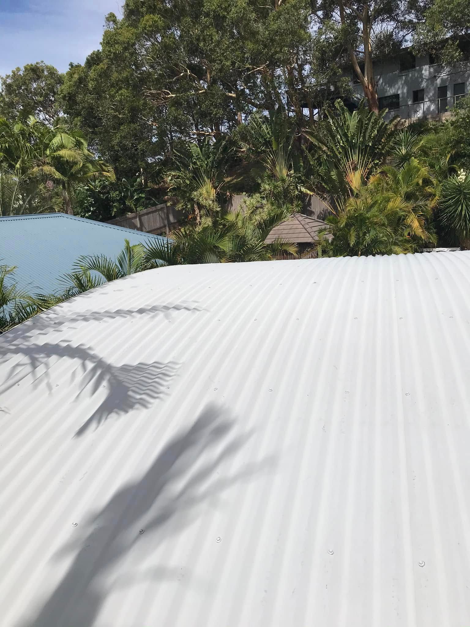 A Man Is Cleaning A Wooden Deck With A High Pressure Washer — The Guttering Cleaning Man in Taree, NSW