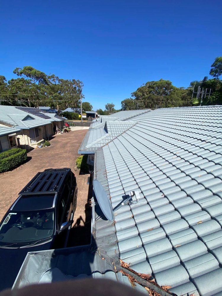 A Car Is Parked On The Roof Of A House — The Guttering Cleaning Man in Old Bar, NSW