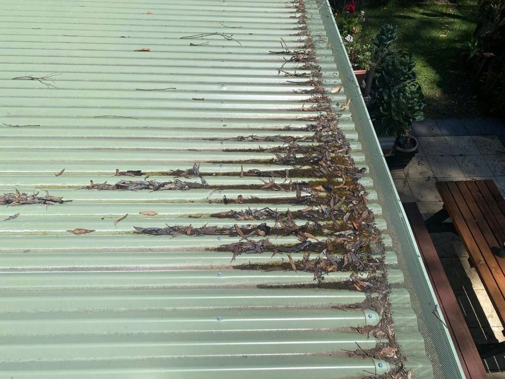A Roof With A Gutter Filled With Leaves On It — The Guttering Cleaning Man in Old Bar, NSW